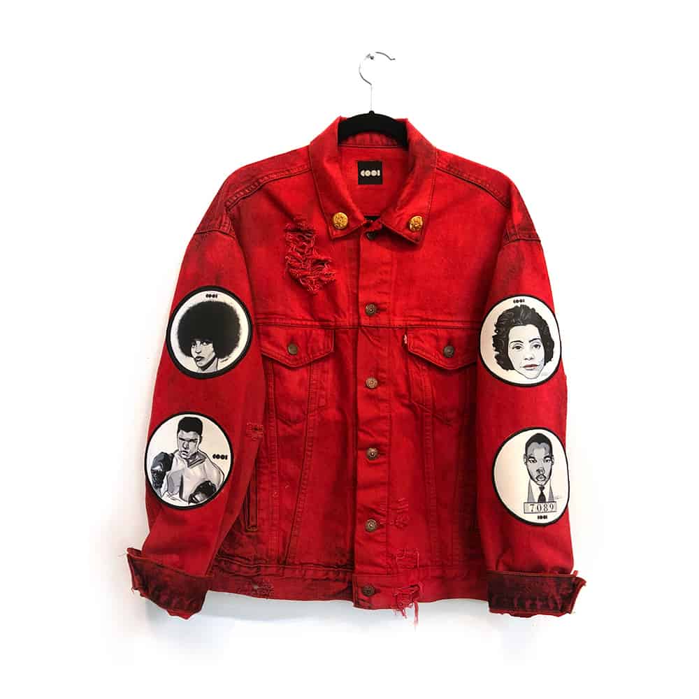 Red denim jacket with black and white patches and pins on it 